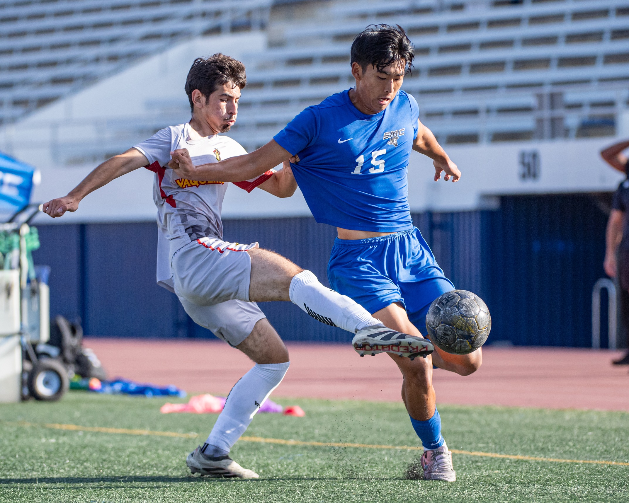Blue Jersey Santa Monica's Soccer Player with ball running past a white jersey defender.