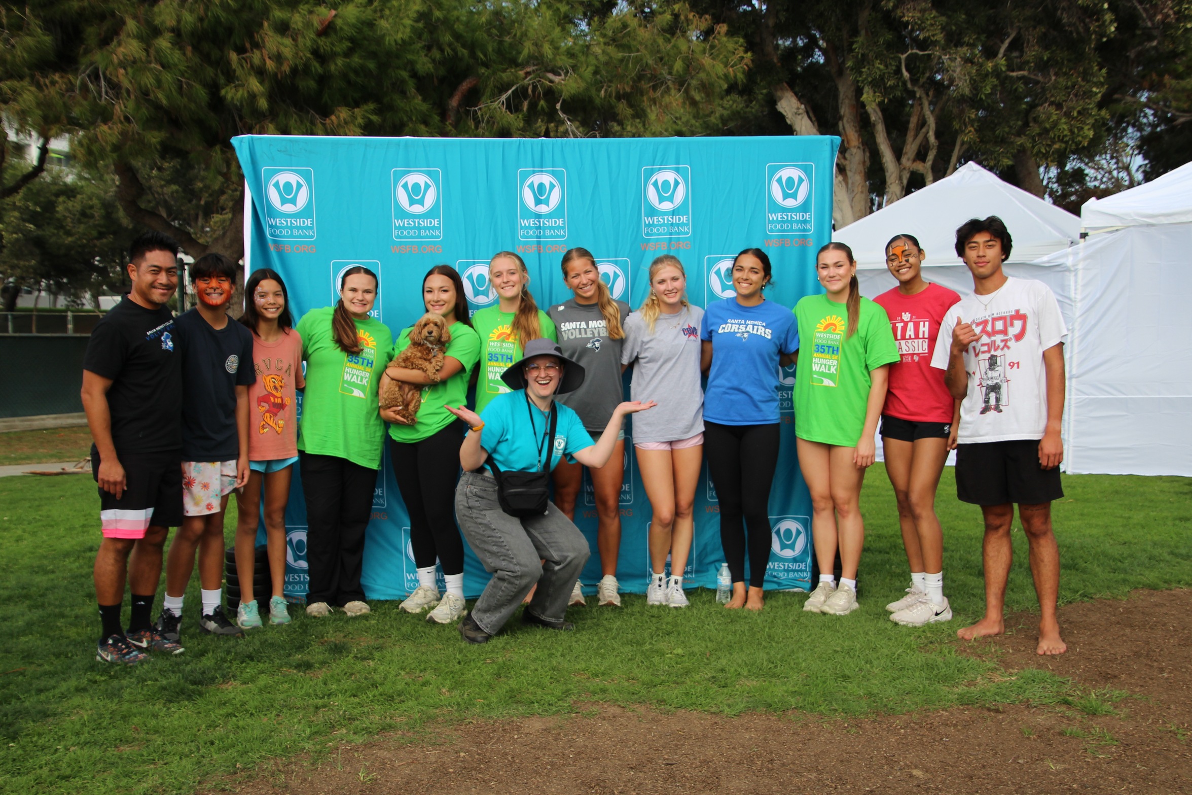 group of students and volunteers pose in front of the hunger walk banner