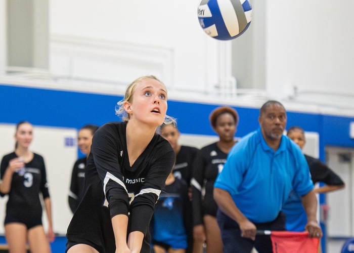female volleyball player in black jersey digs a volleyball
