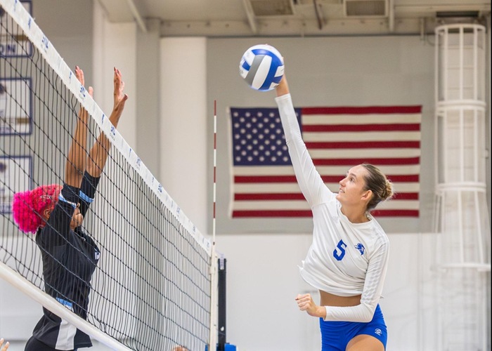 Volleyball player for Santa monica spiking a ball against an opponent at the net